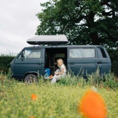 a woman sitting in a van in a field of flowers