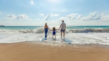 man, woman and child holding hands on seashore